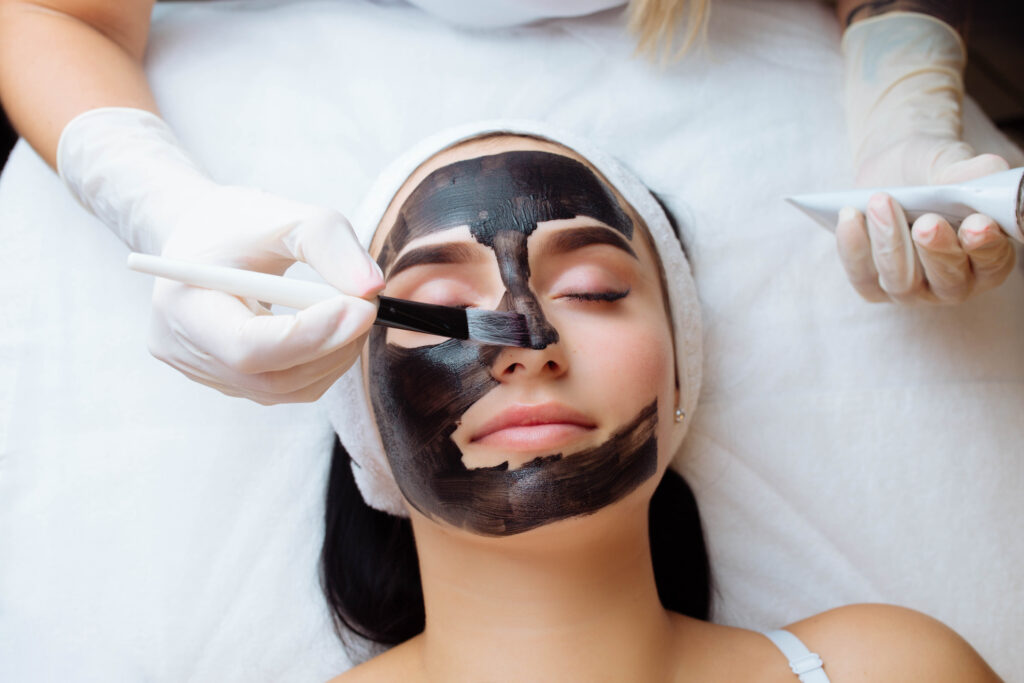 Aesthetician applying mask during clarifying facial treatment
