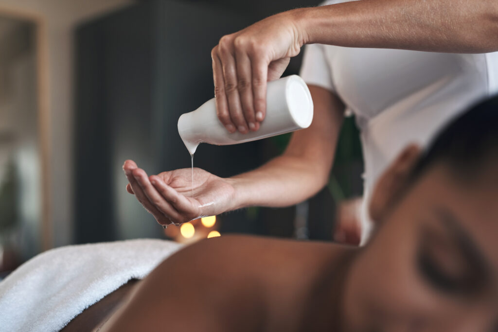 Massage therapist pouring oil on her hands